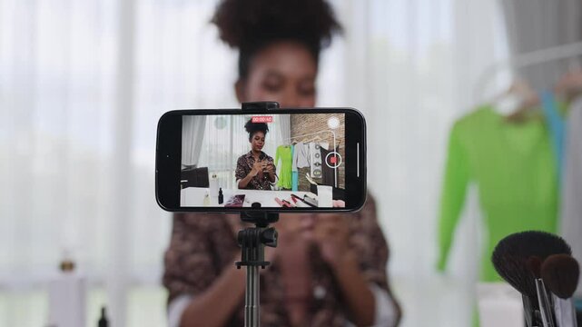 Rear view phone screen recording woman influencer shoot live streaming vlog video review makeup crucial social media or blog. Young girl with cosmetic for marketing broadcasting online.