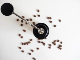 manual coffee grinder black on a white background. There are coffee beans nearby, top view