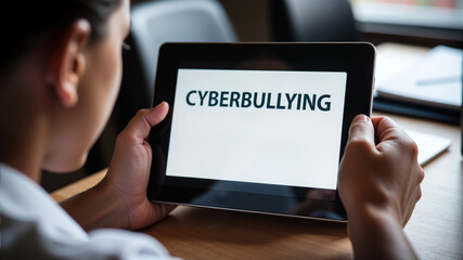 A person reading the word "CYBERBULLYING" on a tablet in a modern workspace – Digital safety awareness, Cyberbullying concept, Safer Internet Day