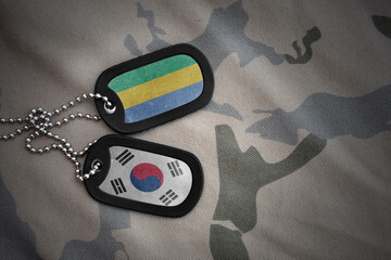 vintage army blank, dog tag with flag of gabon and south korea on the khaki texture background....