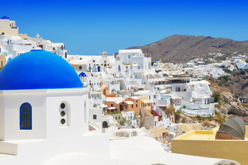 Fototapeta premium Oia village on Santorini island, Greece. Traditional and famous church with blue dome and white houses over the Caldera, Cyclades islands Aegean sea. 