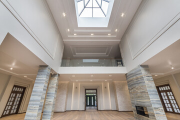 Obraz premium An empty living room with a fireplace in a luxurious mansion. A glass dome in the .opening of the high ceiling. Unfurnished.