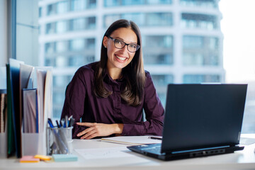 Portrait of confident European woman CEO or manager wearing glasses, sitting at workplace with...