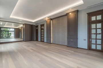 A delightful living room design in a luxurious mansion. Mirrored wall, panoramic windows, dark doors with frosted glass windows. Unfurnished.