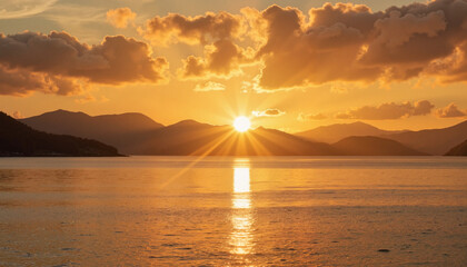 Sunset on the coast with the sun setting behind the mountains and shimmering water