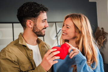 Joyful Couple Celebrating Love with Heart Shaped Soft Toy in a Cozy Indoor Space, Capturing...