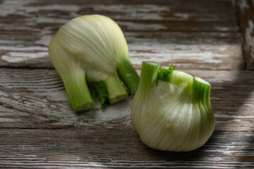 Freshly cut fennel bulbs resting on rustic wooden surface bathed in warm light