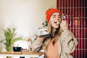 Happy young woman eating a delicious piece of cake in a coffee shop