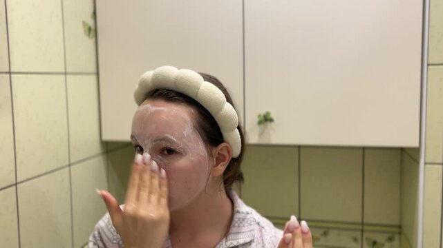 young teeneger girl making white facial mask in her own green bathroom. skincare, face cream morning evening rotine