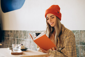 Smiling woman reading a book and drinking coffee in a cafe