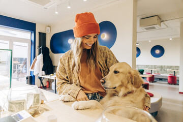 Smiling woman with golden retriever in dog-friendly cafe