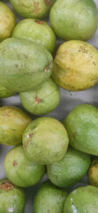 Fresh green and yellow guava arranged together on a surface in a market setting
