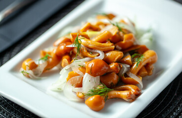 Close-up of marinated mushrooms garnished with fresh dill and onions on a white plate