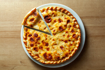 Traditional Russian pie with a golden crust and one slice cut presented on a white plate