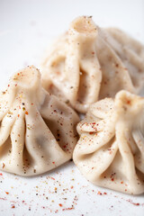 Close-up of traditional khinkali dumplings sprinkled with spices on a white plate