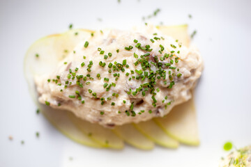 Close-up of a creamy chicken salad garnished with chopped chives served on thinly sliced pears