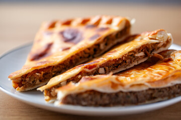Close-up of sliced traditional Russian meat pie on a white plate with a focus on the filling and golden crust