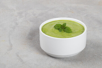 Pea mint cream soup puree. In a bowl. Light gray background. Copy space
