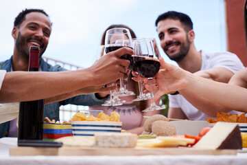 Multiethnic group of friends enjoying together in a rooftop cheering with red wine celebrating. Image with copy space.