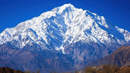 Majestic snow-capped mountain peak against a clear blue sky.