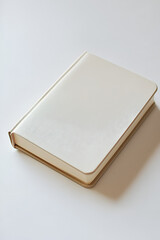 Fototapeta premium Cream-colored notebook with a textured cover, resting on a white surface. Perfect for minimalist designs.