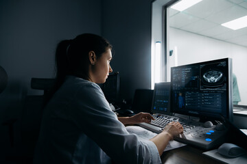 A doctor reviews X-ray images in the MRI control room while monitoring the patient's examination....
