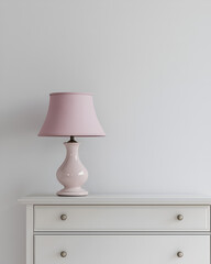 Pink lamp on white dresser against a light wall. Simple and elegant bedroom decor.