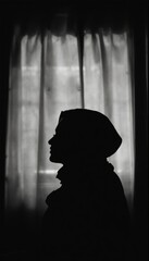 A Woman's Silhouette Against A Curtain Window In Black And White