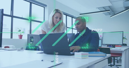 Discussing work at laptop, colleagues in office with data processing image over