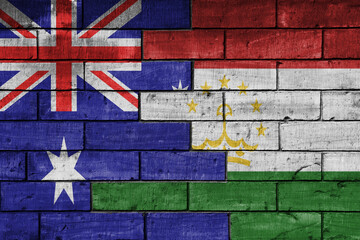 colourful painted big flag of australia and flag of tajikistan on a massive old brick wall...