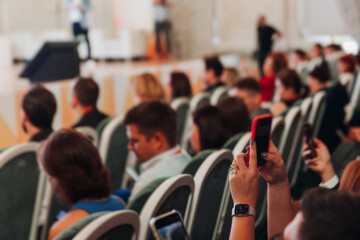 Audience at the modern conference hall listens to panel discussion, people on a congress event together listen to speaker on stage at convention, business seminar, large venue for forum presentation