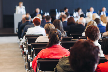 Audience at the modern conference hall listens to panel discussion, people on a congress event together listen to speaker on stage at convention, business seminar, large venue for forum presentation