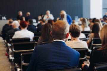 Audience at the modern conference hall listens to panel discussion, people on a congress event...
