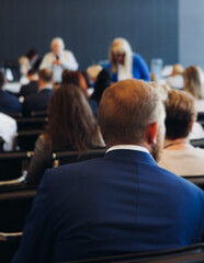 Obraz premium Audience at the modern conference hall listens to panel discussion, people on a congress event together listen to speaker on stage at convention, business seminar, large venue for forum presentation