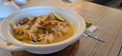 Mie Celor, noodle soup with pork in white bowl on wooden table