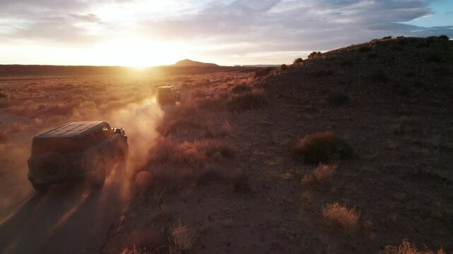 4K Aerial epic dreamy shot of 4x4 SUV offroading vehicles in desert