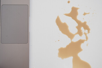 A drink was accidentally spilled on a desk with a laptop and glasses, creating a mess
