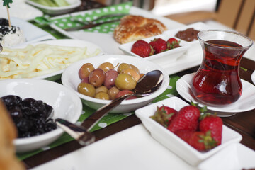 Traditional Breakfast Table Featuring Tea, Fresh Fruits, Olives, and Pastries