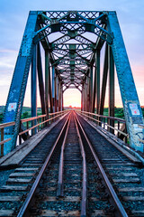 Fototapeta premium A bridge with train tracks and a sunset in the background