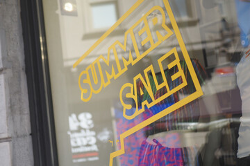 Large red summer Sale text letters on a glass wall obstruct a view inside the popular fashion store