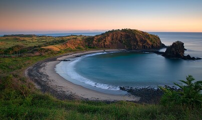 Fototapeta premium Secluded cove beach at sunrise with calm turquoise water and rocky headland