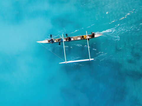 Drone Aerial View of a Canoe Gliding Through Waves in Hawaii's Transparent Blue Ocean