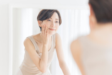 鏡を見ながら頬を触っている女性。
