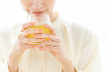 グラスに入った飲み物を飲んでいるミドル世代の女性。