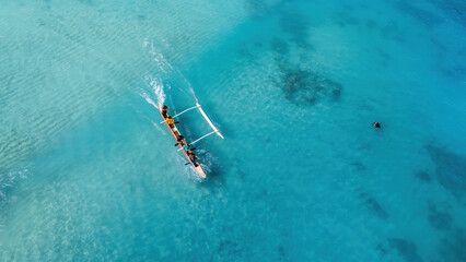 Drone Aerial View of a Canoe Gliding Through Waves in Hawaii's Transparent Blue Ocean