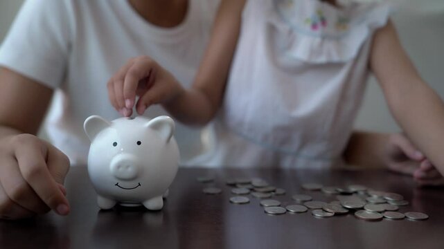 A woman and a child are putting coins into a piggy bank. The woman is teaching the child about saving money Repository for financial responsibility