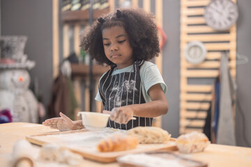 Child enjoys baking while showing creativity in a playful kitchen setting filled with flour and dough
