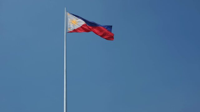 Philippine flag waving in the wind against a blue sky background. 4K footage