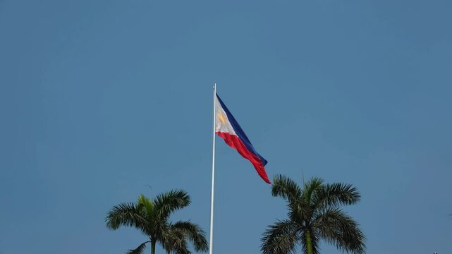 Philippine flag waving in the wind against a blue sky background. 4K footage