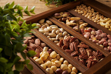 Mix of Nuts in a Wooden Box with Plants Around it.